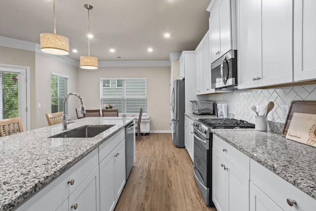 kitchen featuring light wood-style flooring, white cabinetry, decorative backsplash, stainless steel appliances, and a sink