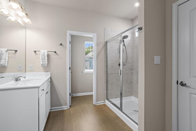 bathroom with a notable chandelier, vanity, baseboards, and a stall shower