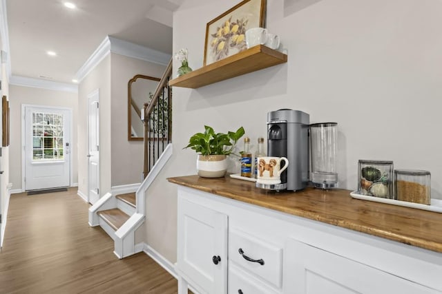 bar with baseboards, ornamental molding, recessed lighting, stairway, and wood finished floors