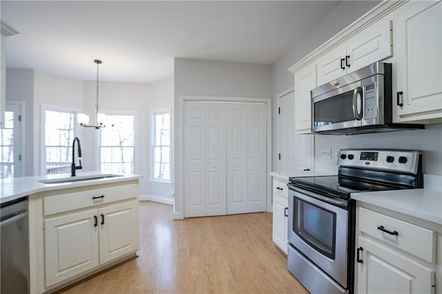 kitchen featuring a sink, stainless steel appliances, light countertops, light wood-type flooring, and a wealth of natural light