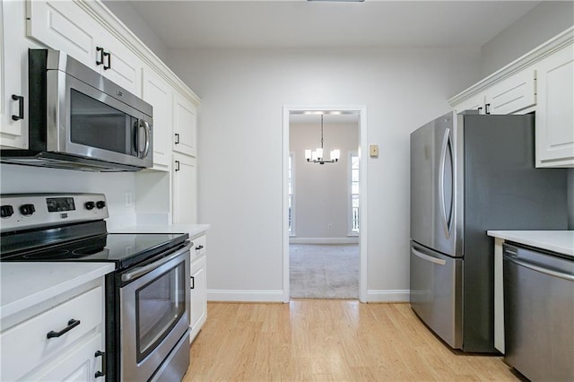 kitchen with white cabinetry, appliances with stainless steel finishes, light countertops, and a notable chandelier