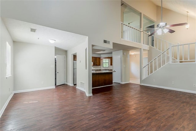 unfurnished living room with dark wood-style flooring, baseboards, a ceiling fan, stairway, and high vaulted ceiling