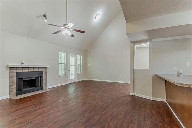 unfurnished living room with a ceiling fan, wood finished floors, baseboards, a fireplace, and a textured ceiling