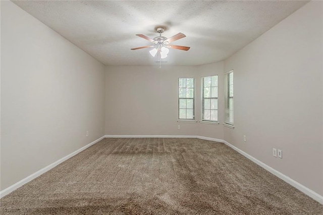 carpeted spare room featuring ceiling fan, baseboards, and a textured ceiling