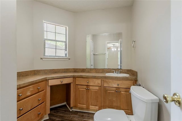 bathroom with toilet, vanity, wood finished floors, and a shower with shower door