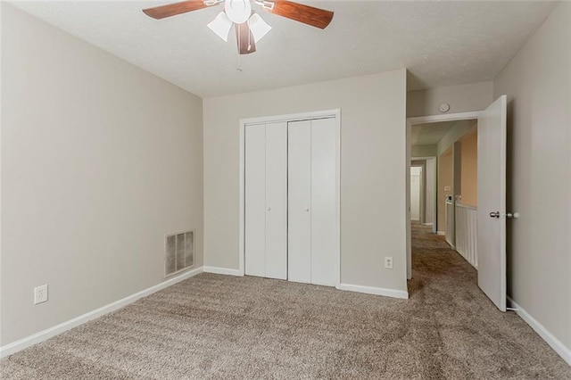unfurnished bedroom with carpet flooring, a closet, baseboards, and ceiling fan
