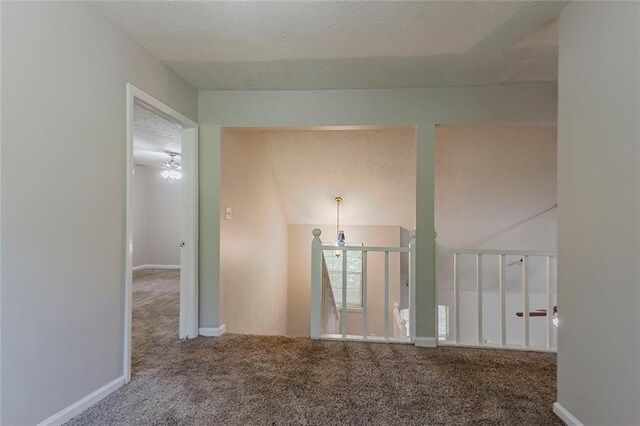 empty room with carpet flooring, baseboards, and a textured ceiling