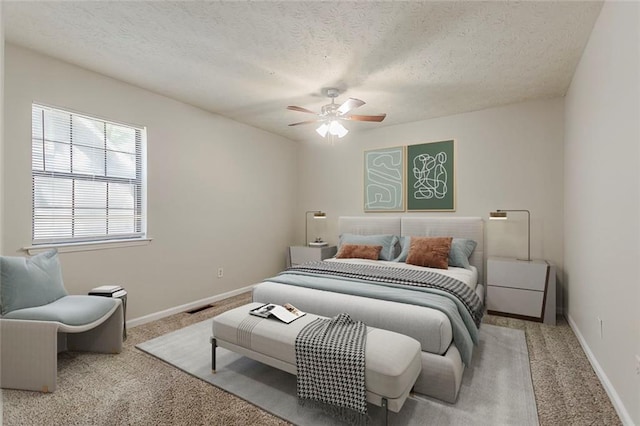 carpeted bedroom featuring a textured ceiling, baseboards, and a ceiling fan