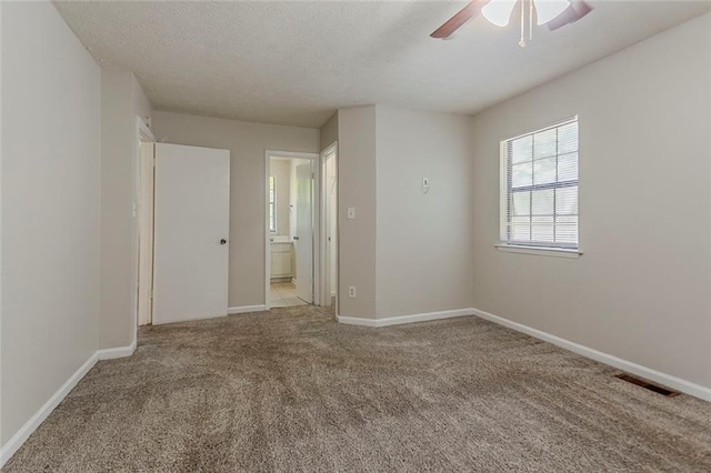 empty room with a ceiling fan, carpet floors, a textured ceiling, and baseboards