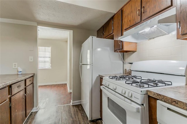 kitchen featuring gas range gas stove, under cabinet range hood, dark wood-style flooring, light countertops, and baseboards
