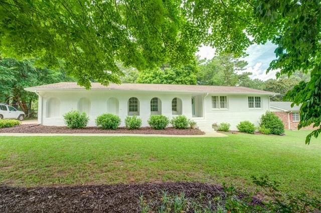 ranch-style house with stucco siding and a front yard