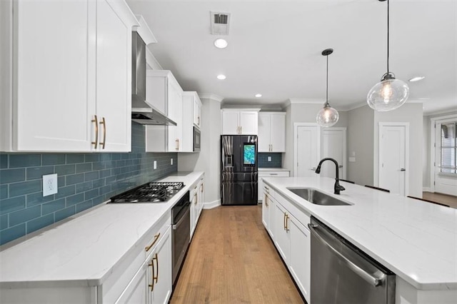 kitchen featuring visible vents, wall chimney range hood, appliances with stainless steel finishes, white cabinets, and a sink