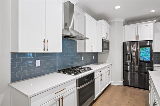 kitchen featuring white cabinetry, wall chimney exhaust hood, wood finished floors, and appliances with stainless steel finishes