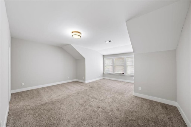 additional living space featuring vaulted ceiling, baseboards, visible vents, and carpet floors