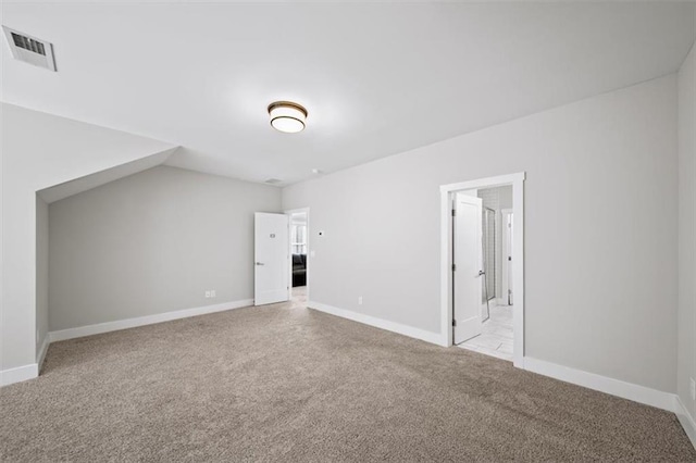 additional living space featuring light carpet, visible vents, and baseboards