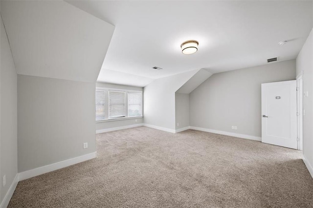 additional living space featuring carpet flooring, visible vents, baseboards, and lofted ceiling