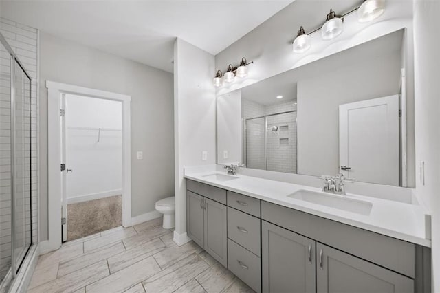 bathroom featuring double vanity, a stall shower, a walk in closet, and a sink