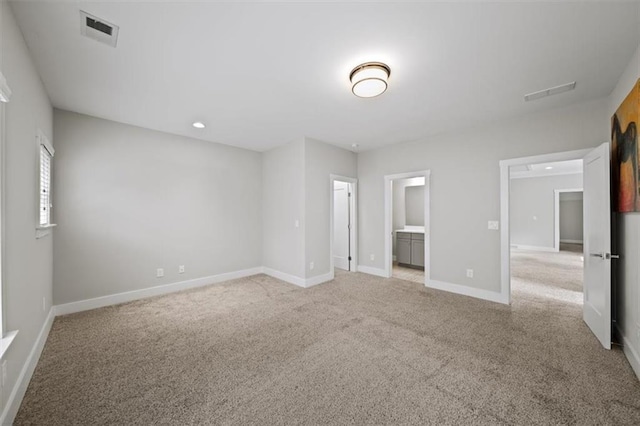 empty room featuring light carpet, visible vents, and baseboards