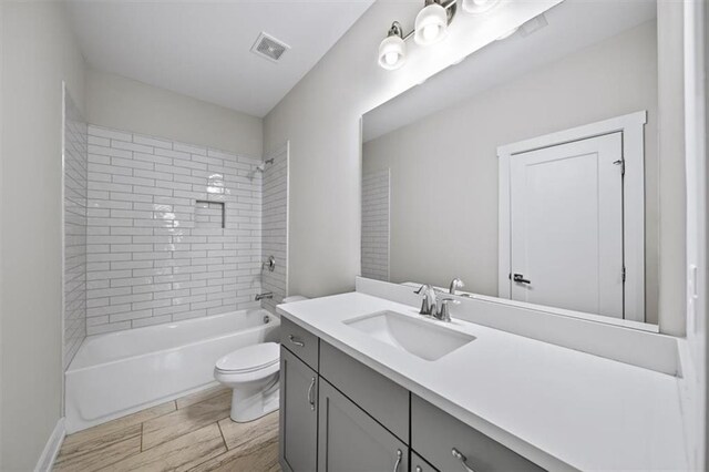 bathroom featuring visible vents, wood finish floors, toilet, shower / bathing tub combination, and vanity