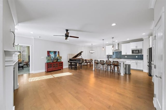 living area with recessed lighting, baseboards, ceiling fan, and light wood finished floors