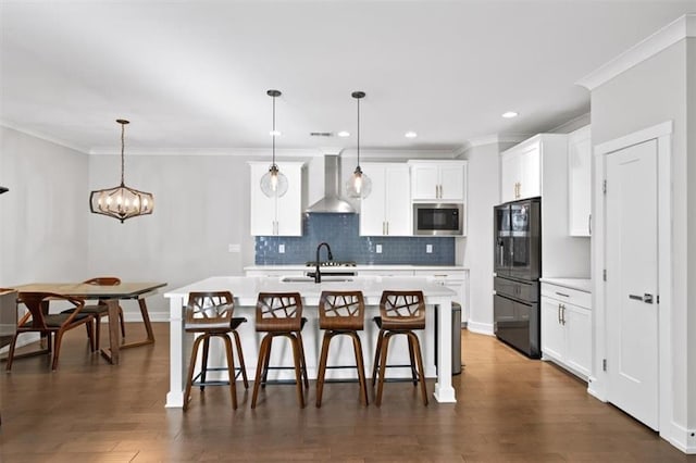 kitchen featuring a sink, stainless steel microwave, freestanding refrigerator, wall chimney exhaust hood, and light countertops