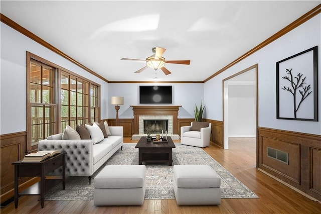 living room with crown molding, light hardwood / wood-style flooring, ceiling fan, and a brick fireplace