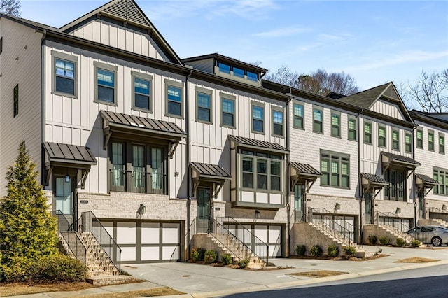 townhome / multi-family property with metal roof, a garage, driveway, board and batten siding, and a standing seam roof