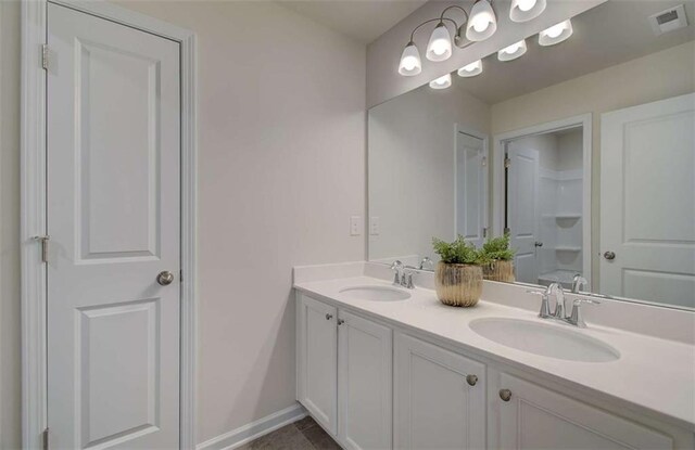 full bath with a sink, visible vents, baseboards, and double vanity