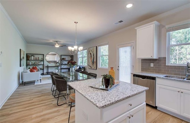 kitchen featuring stainless steel dishwasher, ornamental molding, visible vents, a center island, and open floor plan