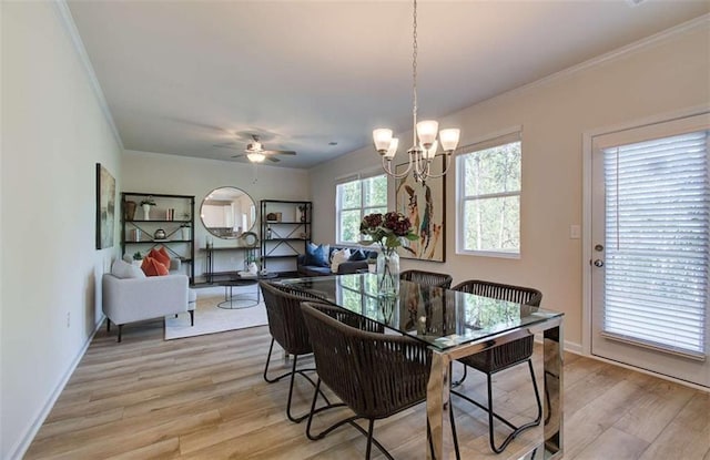 dining area featuring light wood-type flooring, ceiling fan with notable chandelier, crown molding, and baseboards