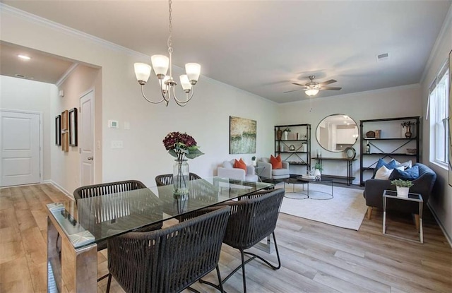 dining space featuring crown molding, visible vents, light wood-style floors, and ceiling fan with notable chandelier