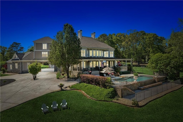 back of house with a fenced in pool, a lawn, and a patio