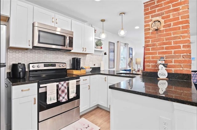 kitchen with light hardwood / wood-style flooring, kitchen peninsula, sink, white cabinets, and appliances with stainless steel finishes