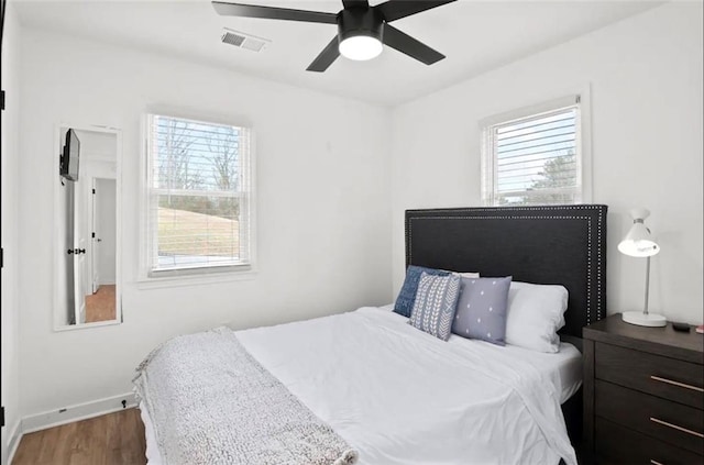 bedroom featuring dark hardwood / wood-style flooring, multiple windows, and ceiling fan