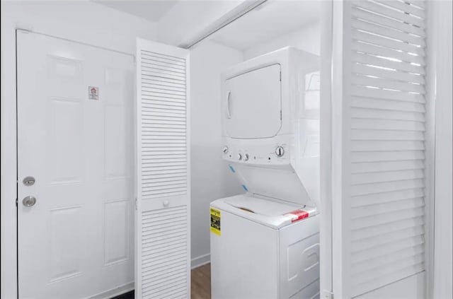 washroom with dark wood-type flooring and stacked washing maching and dryer