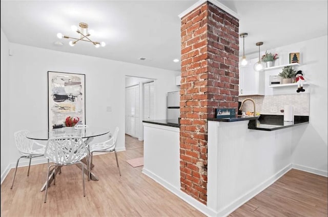 kitchen featuring backsplash, hanging light fixtures, white cabinetry, light hardwood / wood-style floors, and white refrigerator