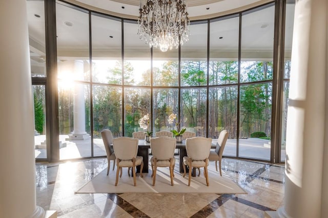 dining space featuring decorative columns, an inviting chandelier, and a wall of windows