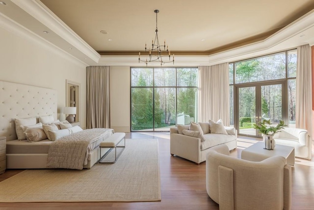 bedroom with access to exterior, french doors, a raised ceiling, hardwood / wood-style flooring, and ornamental molding