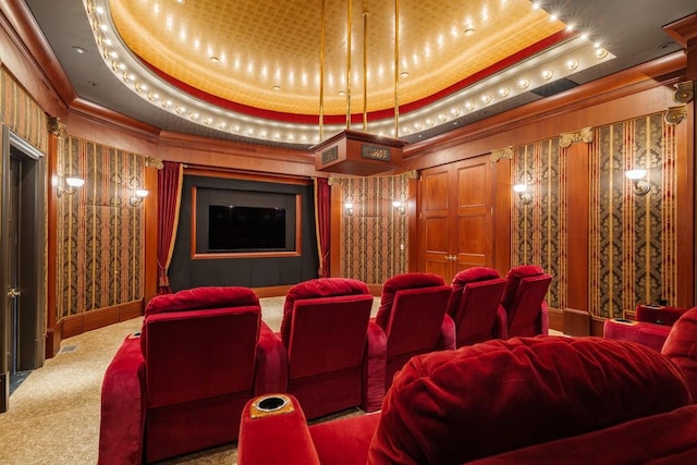 home theater room featuring carpet flooring, a raised ceiling, and ornamental molding