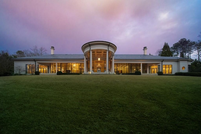 back house at dusk featuring a yard