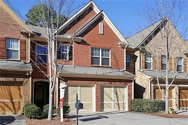 view of property with concrete driveway, an attached garage, and brick siding