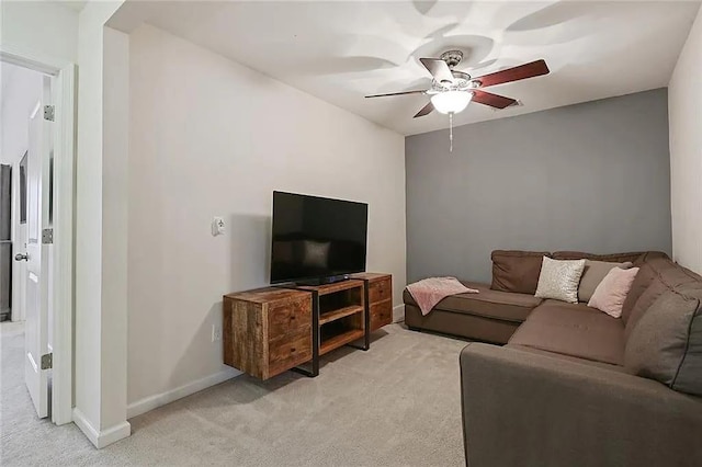 living room featuring baseboards, light carpet, and a ceiling fan