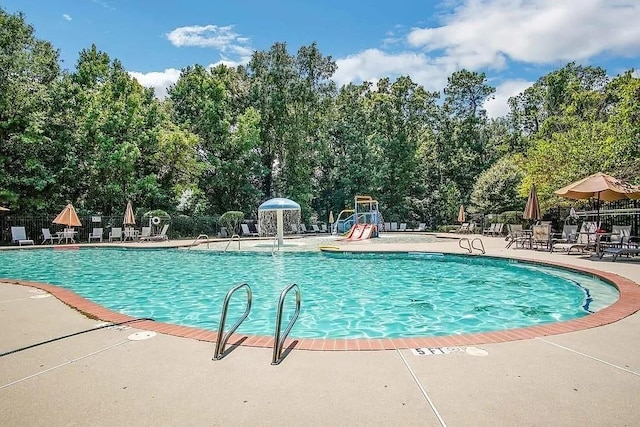 community pool with playground community, a patio area, and fence