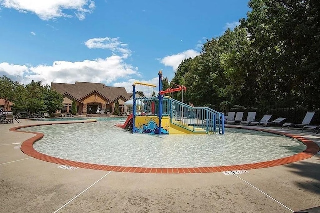 community playground featuring a patio, a community pool, and a water play area