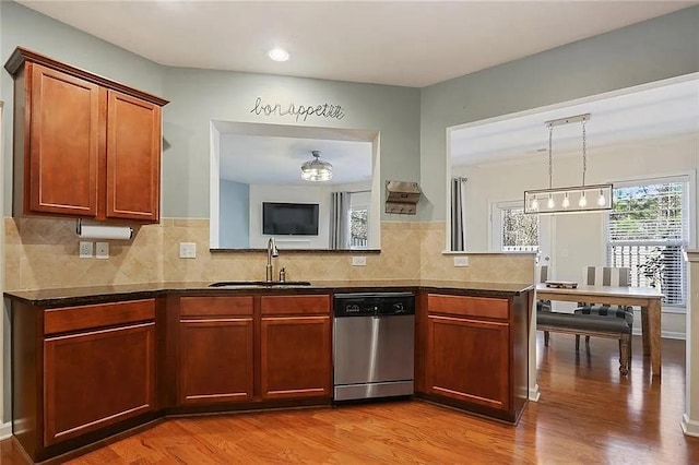 kitchen featuring pendant lighting, a sink, tasteful backsplash, light wood-style floors, and dishwasher