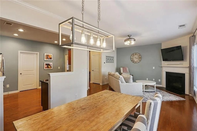 dining room with dark wood finished floors, a fireplace with flush hearth, baseboards, and visible vents