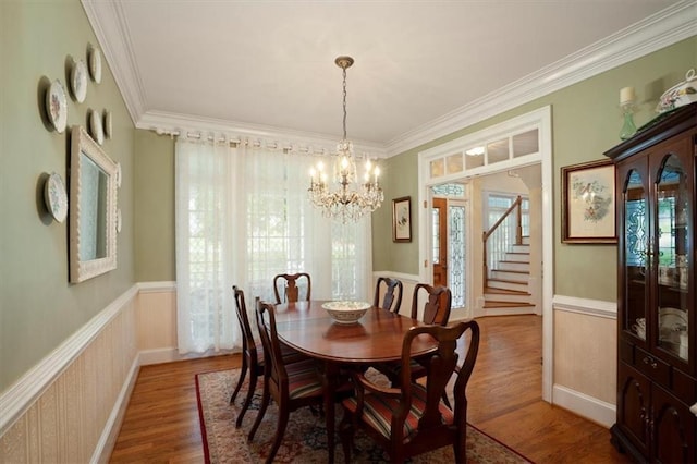 416 Mcdaniel St, Monroe, GA 30655 - dining space featuring a chandelier, a wainscoted wall, ornamental molding, wood finished floors, and stairway