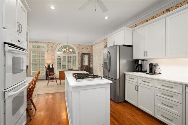 416 Mcdaniel St, Monroe, GA 30655 - kitchen featuring wallpapered walls, white appliances, a center island, a chandelier, and white cabinets