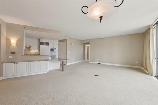 unfurnished living room with light carpet and baseboards