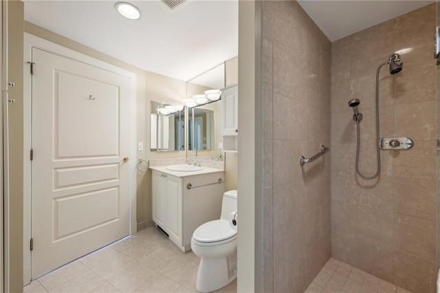 bathroom with tiled shower, vanity, toilet, and tile patterned flooring